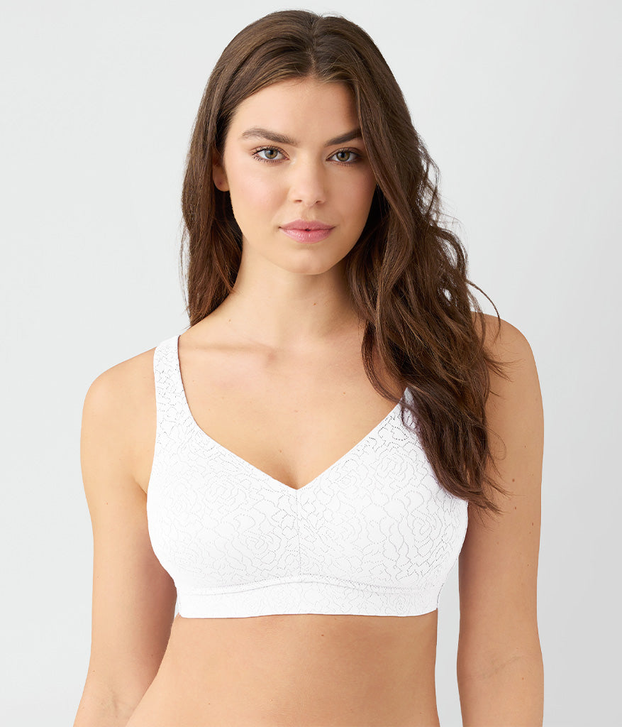 Woman wearing a white textured wireless bra, front view against neutral background